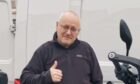 Steven Twizell standing with his thumb up in front of a white van with his motorcycle.