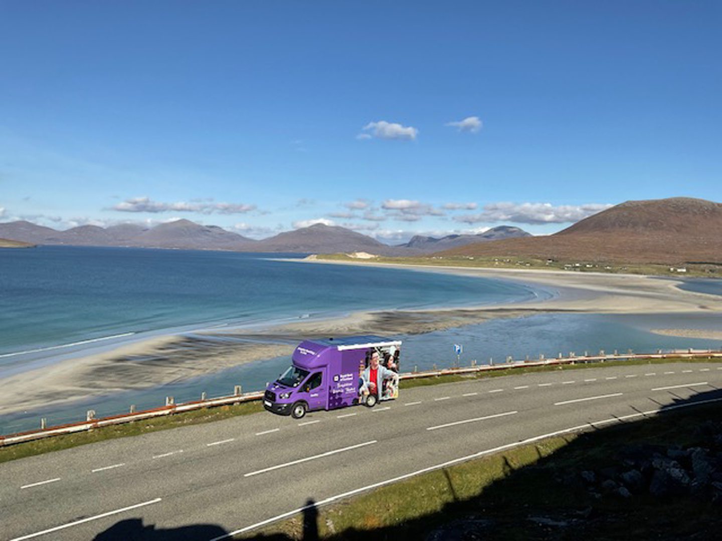 Luskentyre beach in the background with the Lewis and Harris bank van parked at the side of the road.