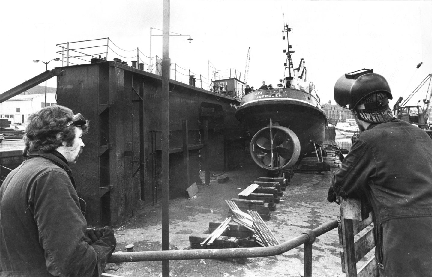 Ship maintenance men Andy McTurk, left, and Steve Mitchell, look on at the Aberdeen Harbour Board tug Sea Trojan in the harbour's No. 1 pontoon dock.