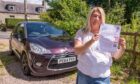 Anita Presslie holding a letter in front of her Citroen.