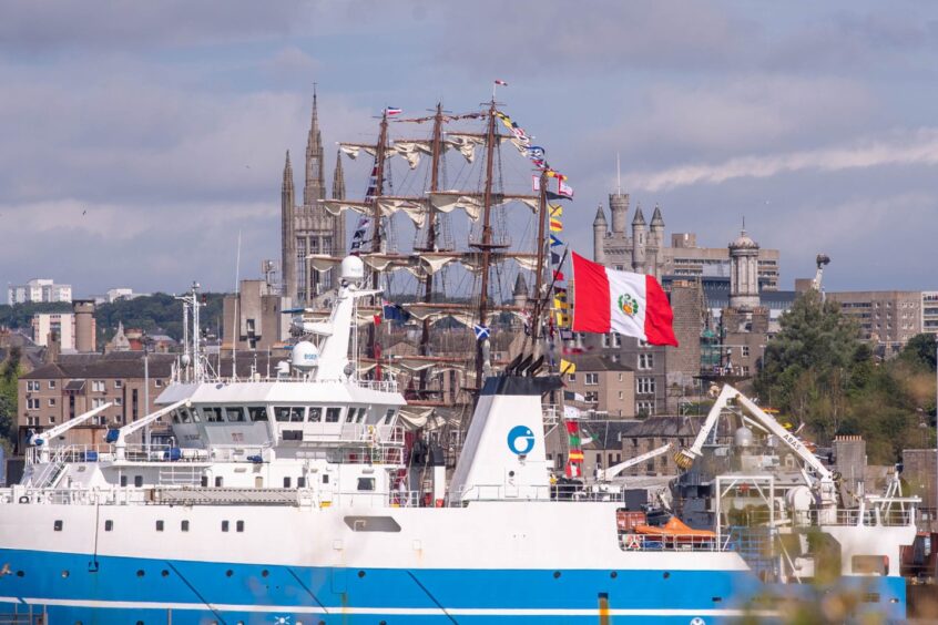 BAP Unión tall ship flying the Peruvian flag docked in Aberdeen Harbour with historic city landmarks in the background.