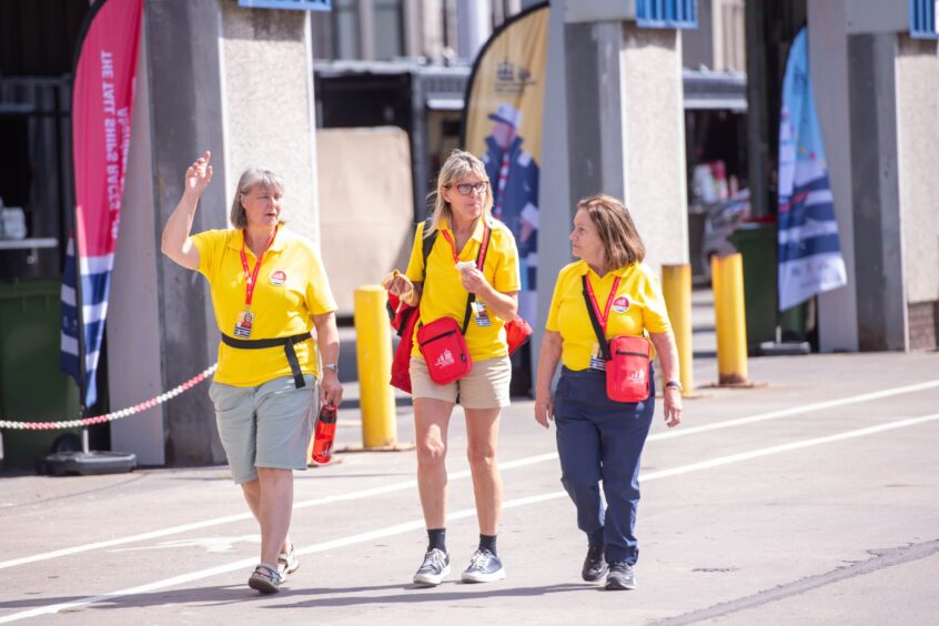 Three volunteers in yellow shirts and red lanyards preparing Aberdeen Harbour for the Tall Ships Races 2025.