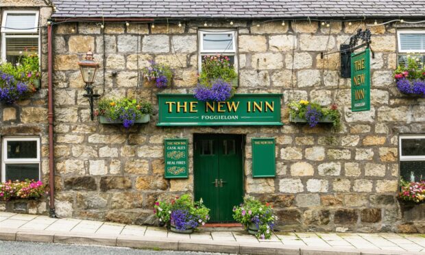 The exterior of The New Inn, with green signage.