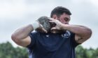 Close-up of Sinclair Patience gripping a stone before throwing during the stone putting event at the 2025 Forres Highland Games in Grant Park.