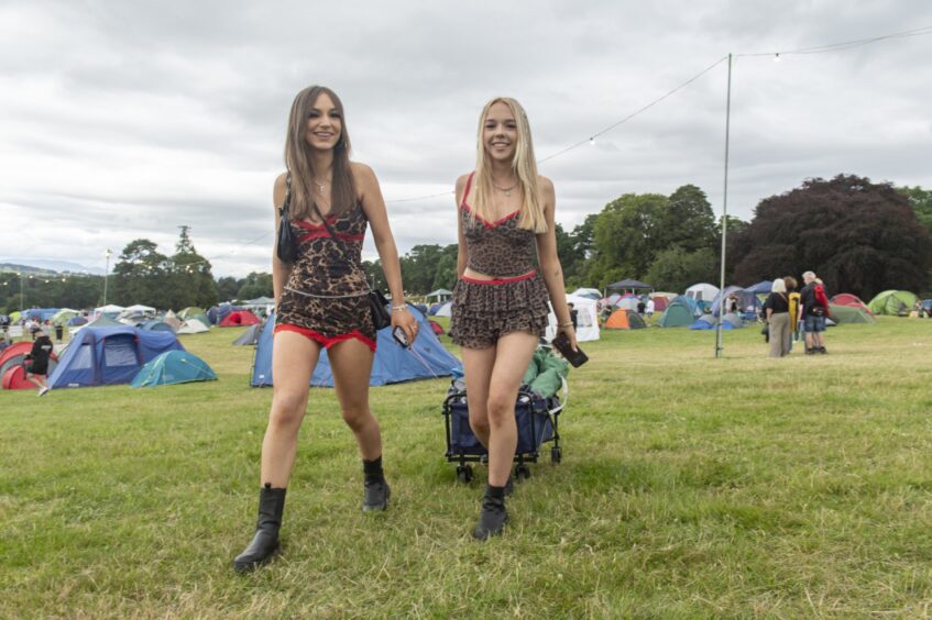 Two young women make their way to the campsite dragging a trailer with all they need for a weekend of camping.