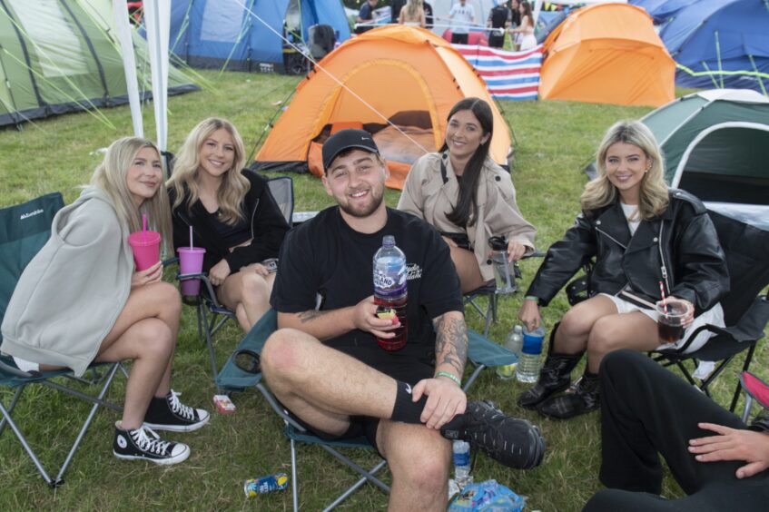 A group of young people gather under a canopy to drink and chat as the festival begins.