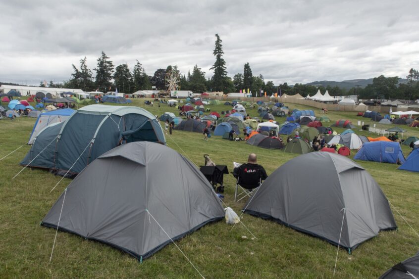 A grassy hill covered in tents.