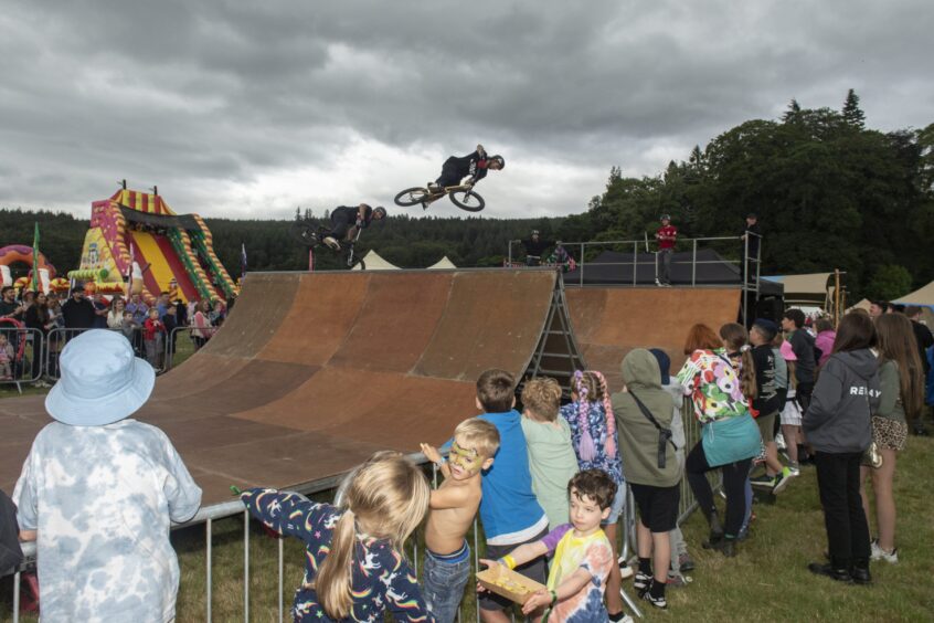 A cyclist jumps off the metal ramp set up in front of an impressed crowd.