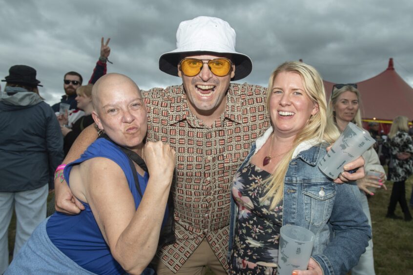 A group of three festivalgoers smile at the camera.