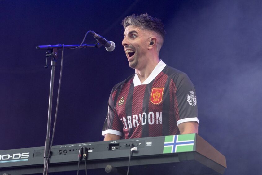 The keyboard player of Torridon smiles at the crowd.