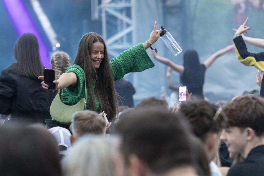 A group of young women sit are raised up to stand head and shoulders above the rest of the crowd.