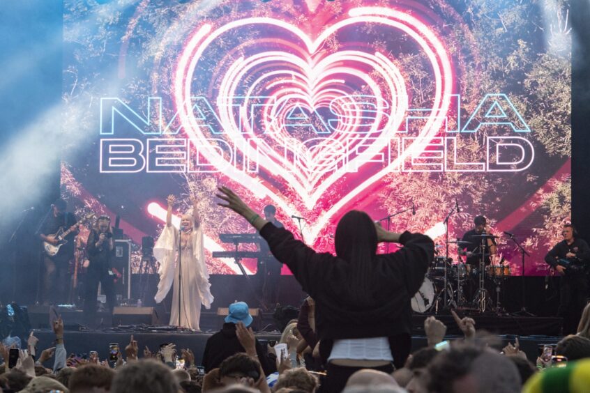 Natasha Bedingfield and her band take the stage backed by her name and hearts on a screen behind her.