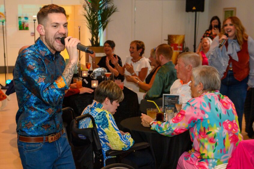 Male and female singers perform among seated guests at That 70s Tribute Show in Aberdeen’s Music Hall, with colourful outfits and drinks on tables.
