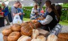 Customers browse and buy sourdough and seeded loaves from The Bread Guy bakery stall at the west end farmers' market in Aberdeen, July 2025.