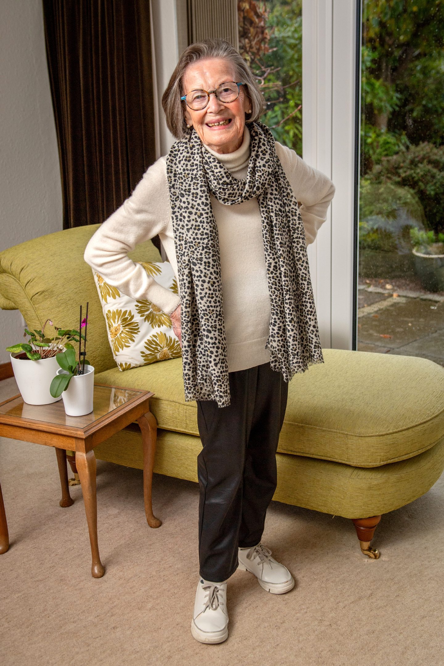 Former Courage model Judy Alexander poses at home in front of a yellow chair.