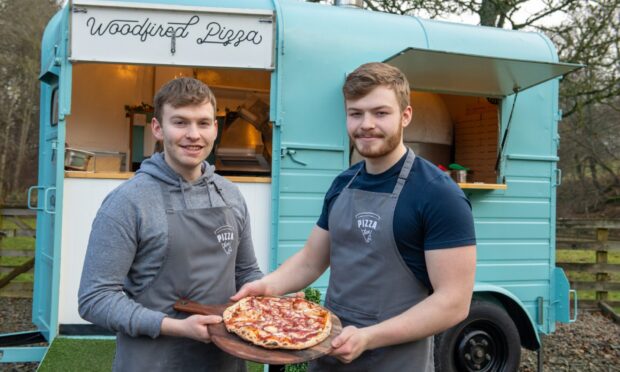 Brothers Rory and Craig Thomson, owners of the Pizza Box Scotland, in front of their blue horse box holding a pizza