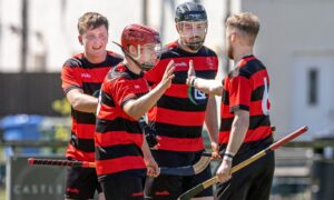 Ross Campbell (red helmet) delights team-mates with the third goal for Oban Camanachd against Lovat. Image: Neil G Paterson.