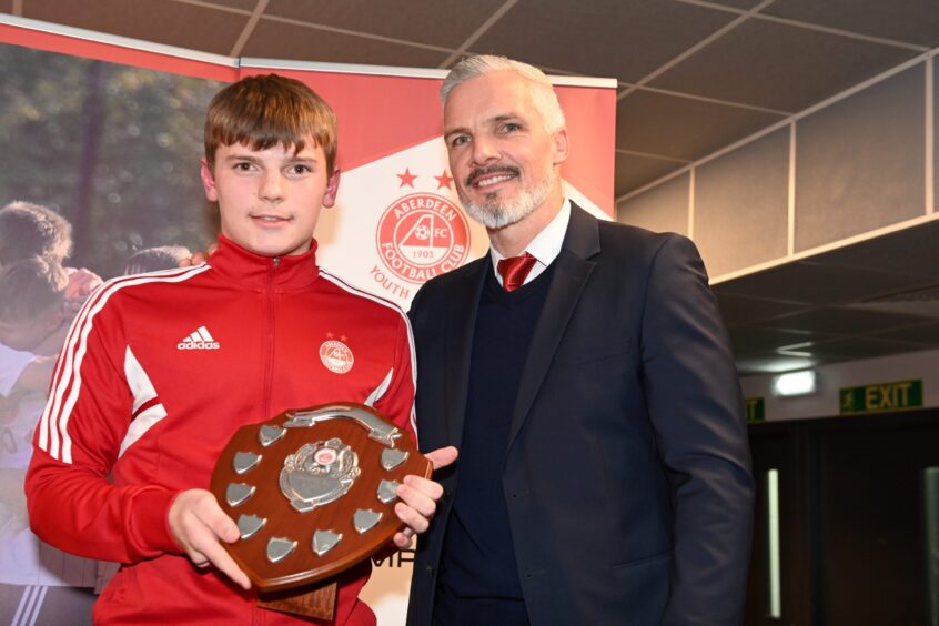 Aberdeen youngster Theo Simpson holds a player of the year trophy, alongside former Dons manager Jim Goodwin.