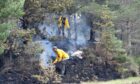 Staff of RSPB Abernethy dampen down hotspots close to the A939 on Dava