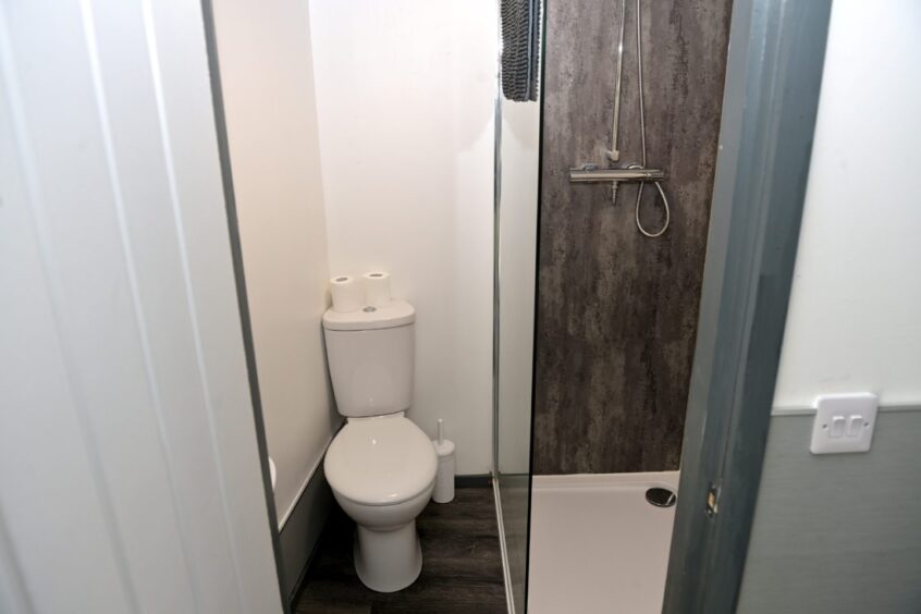 Image shows a small bathroom with a shower and toilet. 