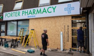 Workmen boarding up the front of the pharmacy.