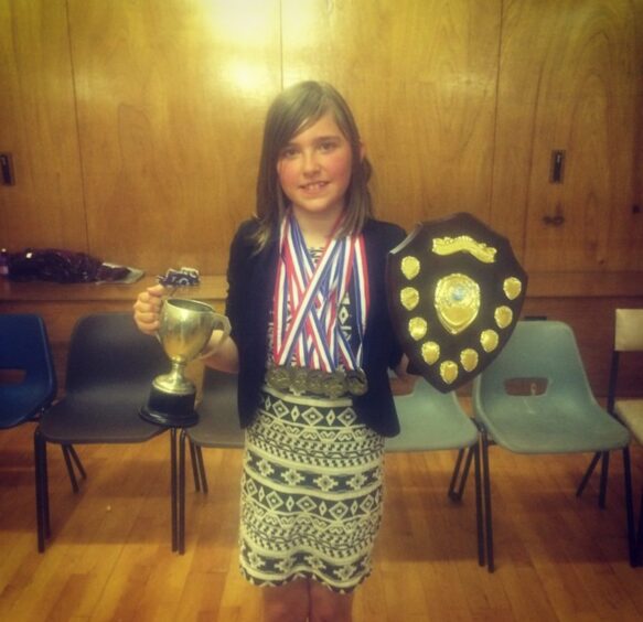 Morgan with her swimming trophies before her brain injury.