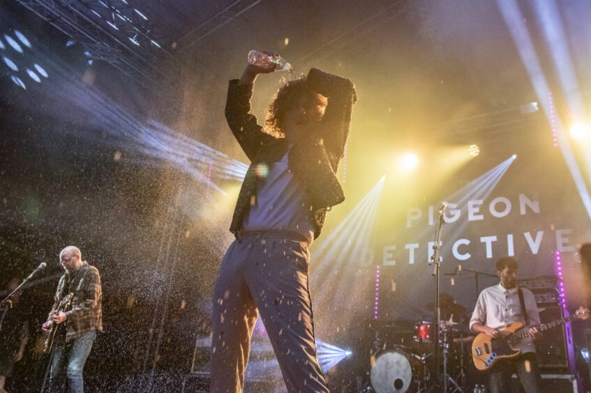 Front man of The Pigeon Detectives band pours water from a plastic bottle over his head.