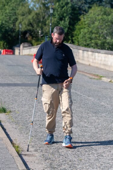 Graham walking with a stick on Aboyne Bridge.