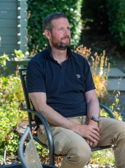 Graham seated outdoors on a garden chair.