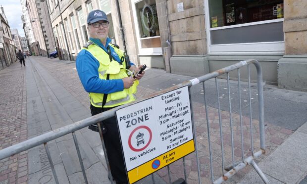 parking warden standing behind sign