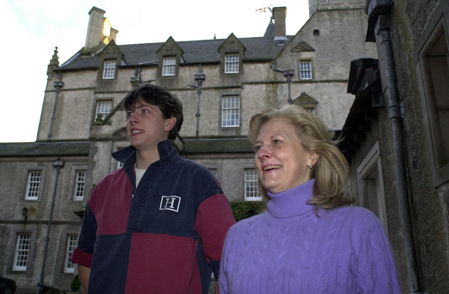 A young Edward Tennant in a rugby shirt standing next to his mum outside Innes House.