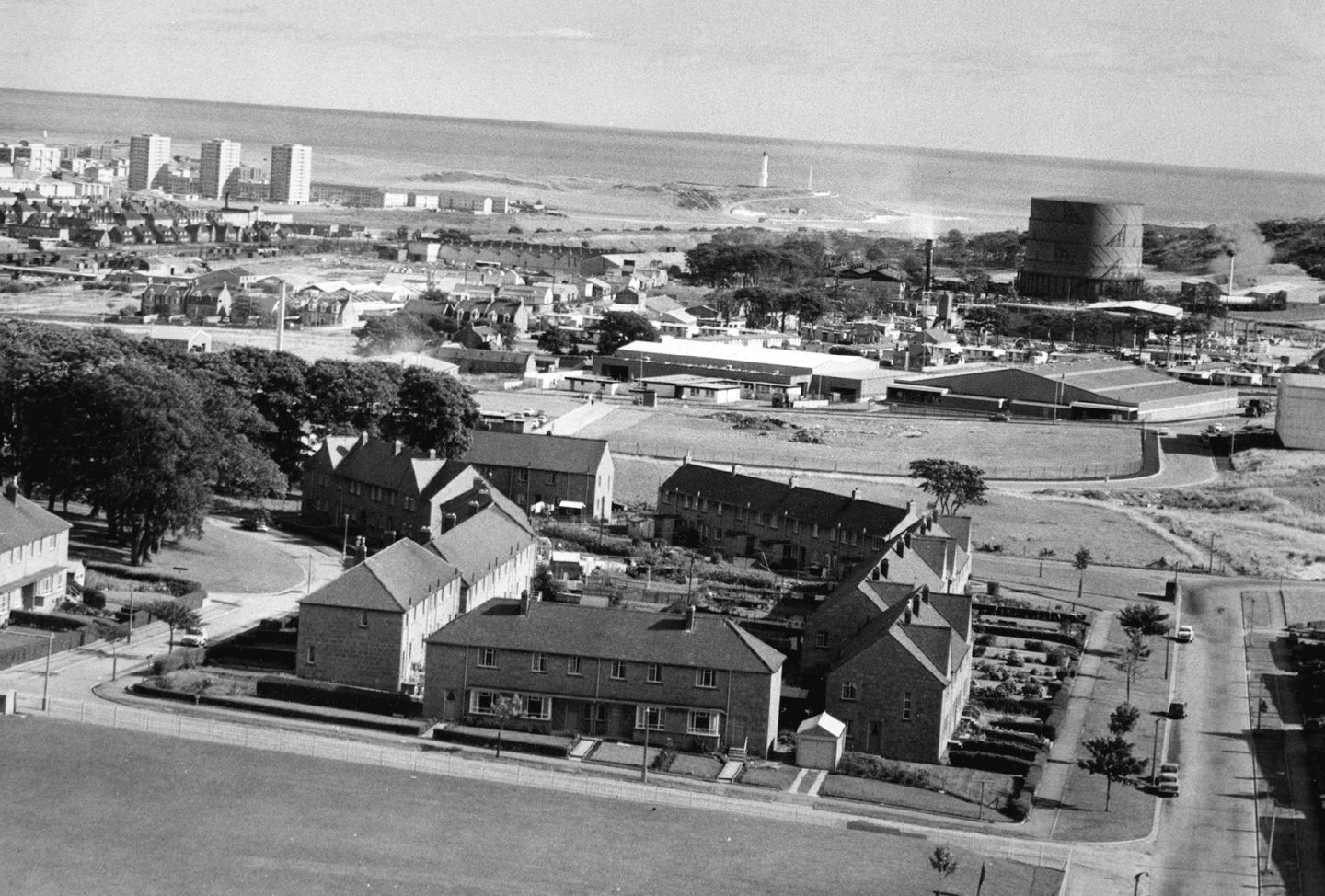 1970: Aerial view of Tullos industrial site, with houses in Cairngorm Crescent in the foreground, the tower blocks of Morven Court, Brimmond Court and Grampian Court can be seen on the left and the lighthouse in Greyhope Road in the distance.