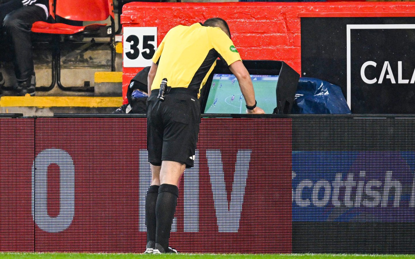 Referee Ross Hardie consults the VAR monitor before ruling out Aberdeen's Kevin Nisbet's strike for offside against Livingston.