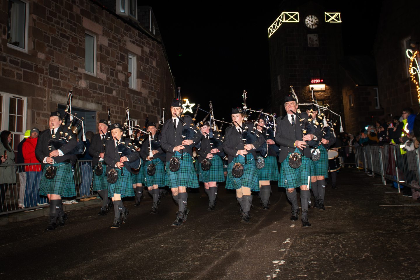 Pipe band marches along Stonehaven High Street during the Fireballs Hogmanay celebrations, with crowds watching on New Year’s Day 2026.