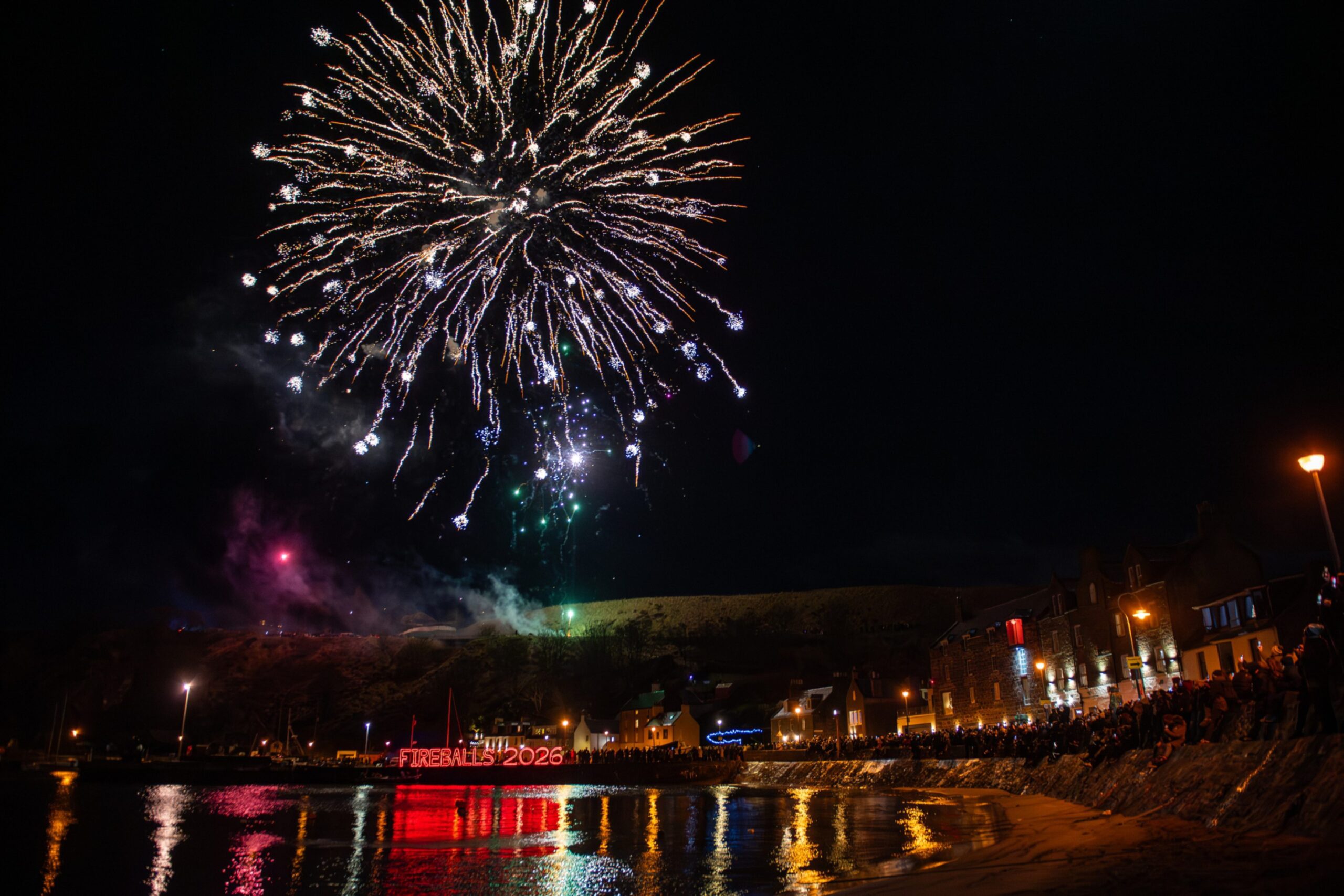 Fireworks explode above Stonehaven Harbour with crowds watching along the waterfront during the Fireballs 2026 New Year celebrations.