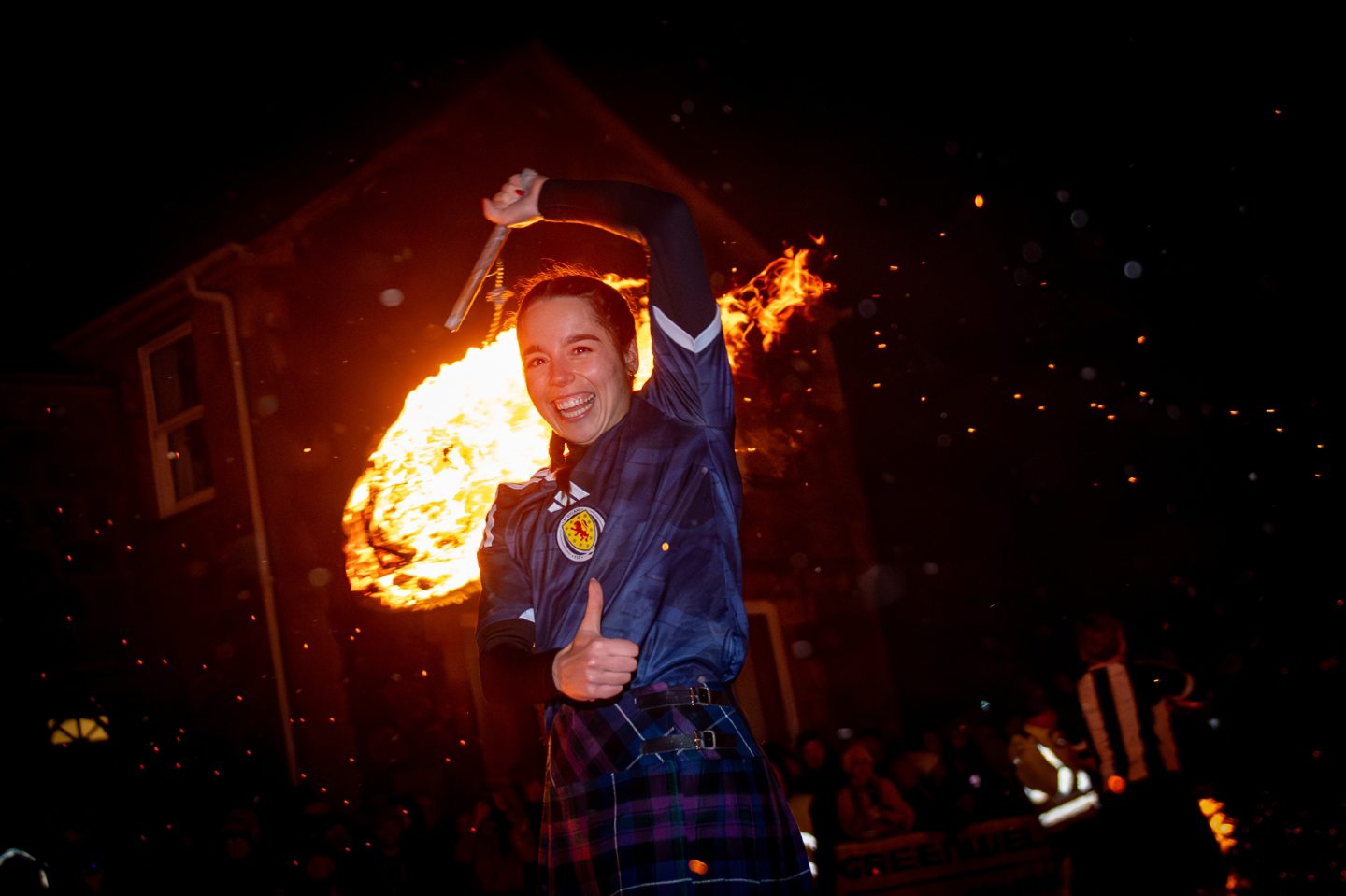 Fireball swinger smiles and spins a flaming fireball during the Stonehaven Fireballs Hogmanay procession on Stonehaven High Street, January 1 2026.