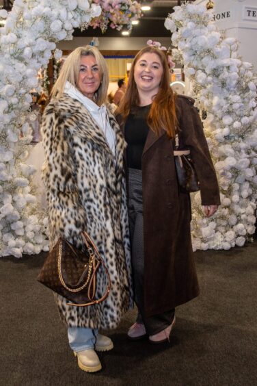 Paula Fraser and Emily Allen standing together beneath a floral arch at Your Wedding Exhibition 2026 inside P&J Live, Aberdeen.
