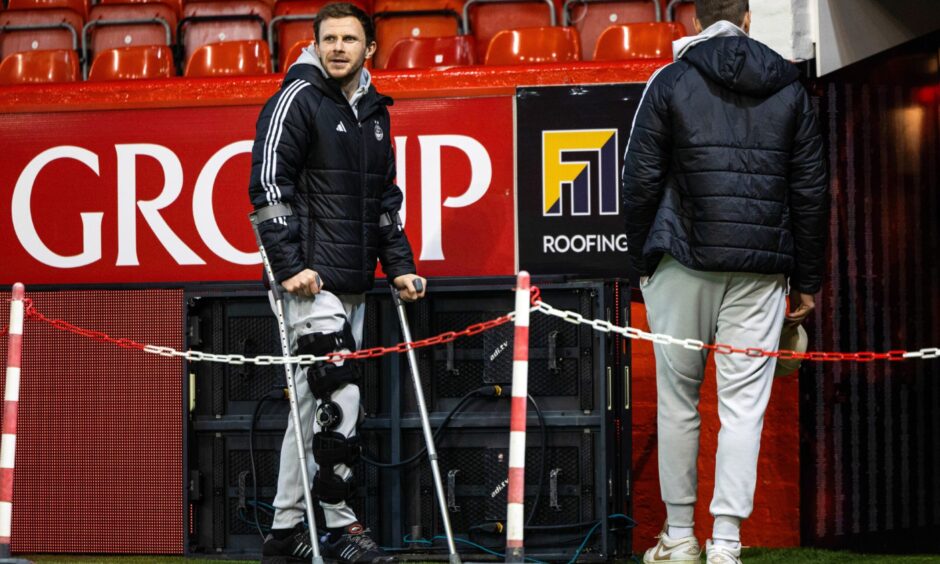 Nicky Devlin pictured on crutches at Pittodrie before the Dons' recent league game against Celtic. Image: SNS.