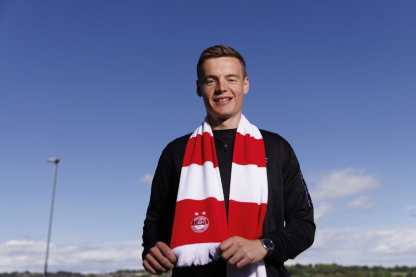 New Aberdeen signing Lewis Mayo at Cormack Park wearing a club scarf.