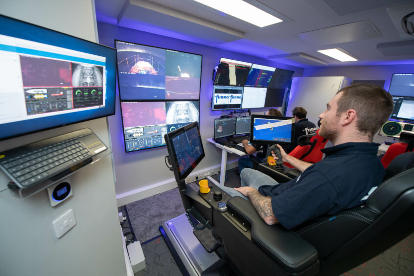 Man in chair looks at lots of screens