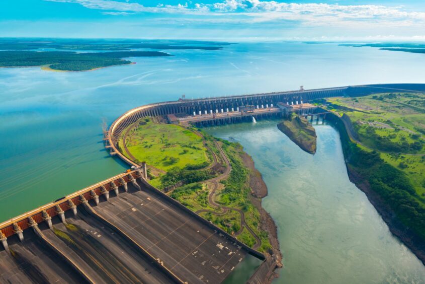 An aerial view of a dam holding back water on the lef