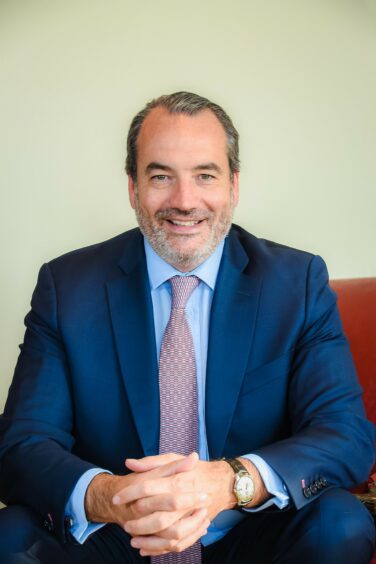 Head shot of man in blue suit on red chair