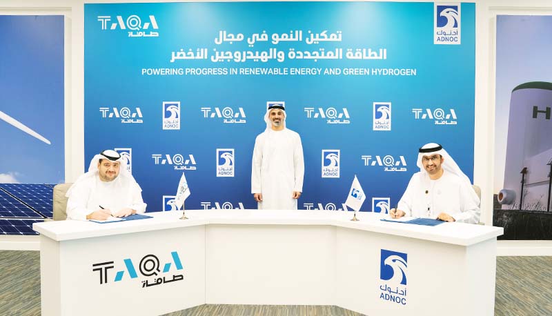 Three men wearing robes behind a logoed desk, behind a blue screen