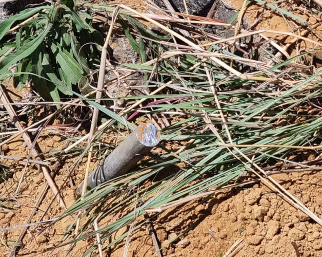 Cut metal rod in orange earth among vegetation