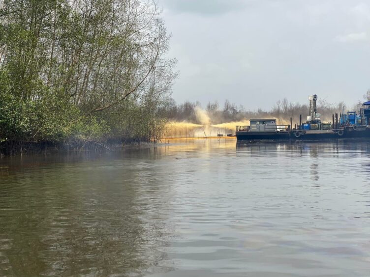 A wellhead sprays liquids to the side and top, in a river