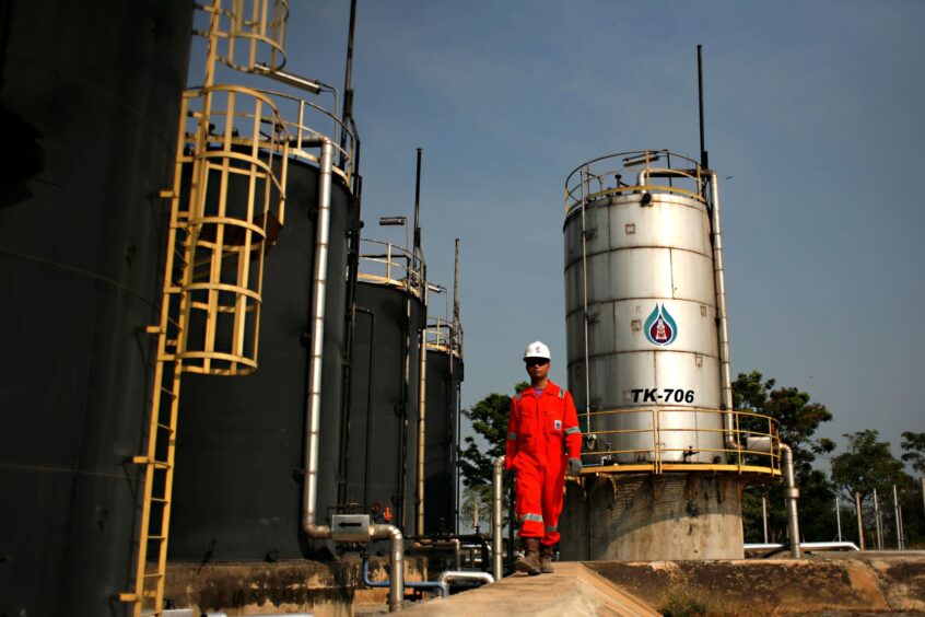 PTTEP production operator walks past crude oil storage tanks at PTTEP 1 Project site's U-Thong petroleum field, in Amphur Muang, Suphanburi province, Thailand, on Wednesday, Feb. 3, 2010.. Photographer: Dario Pignatelli/Bloomberg