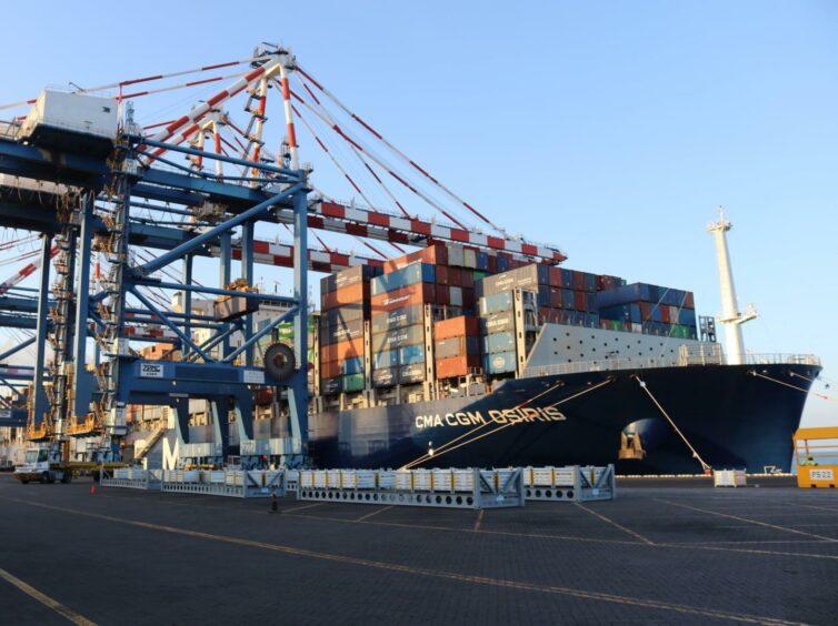 A container ship moored at a terminal, with cranes unloading