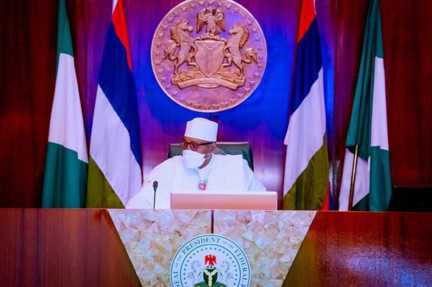 Man sits at desk with Nigerian flags behind