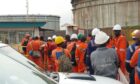 Men in orange overalls line up outside facility