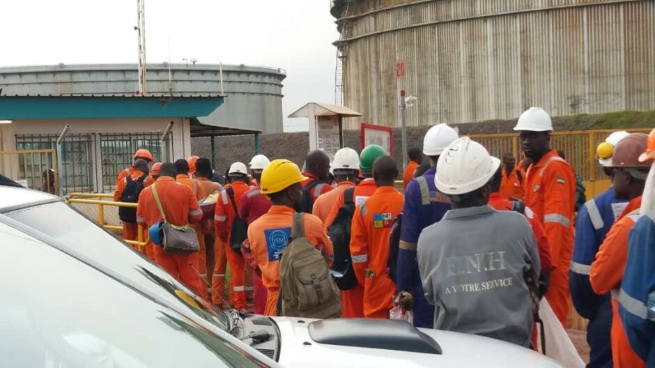 Men in orange overalls line up outside facility